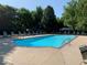Community outdoor pool surrounded by mature trees, lounge chairs, and shade at 8911 Hunters Creek Dr # 311, Indianapolis, IN 46227