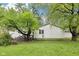 Back exterior view showing the home's white siding complemented by mature trees in a large yard at 90 S Morgantown Rd, Greenwood, IN 46142