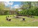 Inviting backyard features a fire pit with wooden benches and lush greenery, perfect for outdoor entertaining at 90 S Morgantown Rd, Greenwood, IN 46142