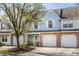 Townhouse with a brick facade, white garage door, and a well-manicured front yard with a young tree at 9575 Thradd St, Fishers, IN 46038