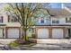 Townhouse with a brick facade, white garage door, and a well-manicured front yard with a young tree at 9575 Thradd St, Fishers, IN 46038