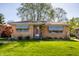 Charming brick home featuring a well-maintained lawn and a distinctive purple front door at 1031 N Lesley Ave, Indianapolis, IN 46219