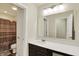 A well-lit bathroom with a large mirror, single sink with dark wood cabinets and tiled shower with curtain at 10811 Wild Orchard Ln, Indianapolis, IN 46239