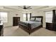 Spacious primary bedroom featuring dark wood furniture, multiple windows and a tray ceiling with fan at 10811 Wild Orchard Ln, Indianapolis, IN 46239