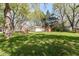 Sprawling backyard with lush green grass, mature trees, and inviting red Adirondack chairs at 11359 Peacock Dr, Indianapolis, IN 46236