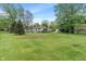 Lush backyard with mature trees surrounds a white house and storage shed at 11415 Central E Dr, Carmel, IN 46032