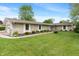 An inviting stone-clad ranch home features a lush lawn, tasteful landscaping, and an attached garage at 11415 Central E Dr, Carmel, IN 46032