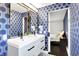 Bathroom featuring double sink vanity, modern mirrors, and patterned blue accent wall at 11626 Forest Dr, Carmel, IN 46033