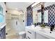 Bathroom featuring walk-in shower with marble tile, double sink vanity, and patterned blue accent wall at 11626 Forest Dr, Carmel, IN 46033