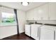 Laundry room with white cabinetry, large window and modern washer and dryer units at 11626 Forest Dr, Carmel, IN 46033