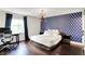 Bedroom featuring patterned blue accent wall, wood floors, and modern light fixture at 11626 Forest Dr, Carmel, IN 46033