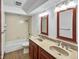 Well-lit bathroom with a double sink, a tub, and cherry wood mirror frames at 11642 Old Stone Dr, Indianapolis, IN 46236