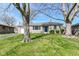 A charming single-story home with stone facade, mature trees, and a blue front door at 1216 N Whittier Pl, Indianapolis, IN 46219