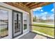 Cozy balcony featuring sliding glass doors overlooking trees, road and lake on a bright sunny day at 13797 E Southshore Dr, Fishers, IN 46037