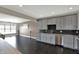 Open-concept kitchen featuring gray cabinets, granite countertops, stainless appliances, and dark hardwood floors at 13797 E Southshore Dr, Fishers, IN 46037