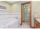 Bathroom with a tub and shower featuring stylish fixtures, tiling, and wooden accents at 168 Yorkshire W Blvd, Cumberland, IN 46229