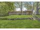 Backyard view with mature trees, a stone wall, and an exterior of the back of the home at 1710 S Butler Ave, Indianapolis, IN 46203