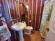 Bathroom with a pedestal sink, decorative mirror and striped wall paper at 23 N West St, Shelbyville, IN 46176