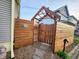 A charming side yard entranceway is lined with wooden fence, stone, and mulch, with a peaked roof above the gate at 23 N West St, Shelbyville, IN 46176