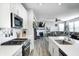 Open kitchen showcasing white cabinets, modern appliances, an island with seating, and seamless flow to the living area at 2428 S Stonehill Way, New Palestine, IN 46163