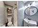 Cozy bathroom featuring open shelving, a toilet and sink with a large rounded mirror and soft neutral paint colors at 260 17Th St, Columbus, IN 47201