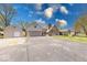 Wide view of the home's exterior with a large driveway, detached garage, and well-maintained lawn at 260 17Th St, Columbus, IN 47201
