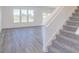 Open living space with stairway, large windows, and gray wood-look flooring at 288 Commodore Dr, Pittsboro, IN 46167