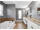 Bathroom features a soaking tub and a double vanity with white cabinets and beige countertop at 5954 Crowley Pkwy, Whitestown, IN 46075