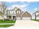 Charming two-story brick home featuring a three-car garage, well-manicured lawn, and inviting front porch at 6040 Juniper Ct, Whitestown, IN 46075