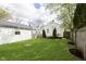 Lush green backyard featuring a detached garage, deck, privacy fence, and neighboring houses at 6180 Crittenden Ave, Indianapolis, IN 46220