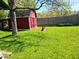Charming backyard with a red storage shed and mature trees, offering a serene outdoor space at 8230 E 11Th St, Indianapolis, IN 46219