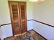 Small hall closet featuring wood slat doors, base trim, and a patterned floor rug at 8230 E 11Th St, Indianapolis, IN 46219