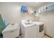 Bright laundry room with white washer, dryer, utility sink, and overhead storage shelves at 838 Deerfield Rd, Anderson, IN 46012