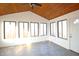 Bright sunroom with vaulted ceiling, wood paneling, large windows and gray vinyl floors at 8911 Country Walk Ct, Indianapolis, IN 46227