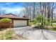 Asphalt driveway leads to a brick home with an attached garage, set amidst mature landscaping and lush greenery at 9309 Golden Woods Dr, Indianapolis, IN 46268