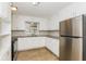 Well-lit kitchen with white cabinets, laminate flooring, and stainless steel appliances, including a refrigerator at 9535 E Michigan St, Indianapolis, IN 46229