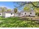 Backyard exterior featuring the home, a sunroom, and a vibrant grassy yard with mature trees at 102 Florence Dr, Greenwood, IN 46143
