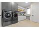 Functional laundry room with modern appliances, gray cabinets, and ample storage shelves at 1333 Chatham Rdg Ct, Westfield, IN 46074