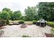 Outdoor patio area with a fire pit, grill, and comfortable seating surrounded by lush landscaping and mature trees at 13717 Van Buren Pl, Fishers, IN 46038