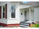 Close up of home with light siding, red brick foundation, and covered front porch at 1509 Sycamore St, Columbus, IN 47201
