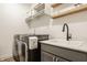 Well-organized laundry room with modern washer and dryer, sink, storage cabinets and floating shelves at 15655 Woodford Dr, Westfield, IN 46074
