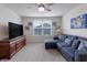 Inviting bonus room with plush carpeting, a large window with blinds, and a comfortable sectional sofa facing the TV at 16080 Cabin Hill Dr, Noblesville, IN 46060