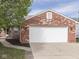 Two car garage featuring red brick exterior, black mulch landscaping and concrete driveway at 212 Westridge Blvd, Greenwood, IN 46142
