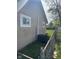 Exterior side view of the house with a small window, utility coverage, and chain link fence at 2448 Winfield Ave, Indianapolis, IN 46222