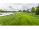 Picturesque backyard with a tranquil pond, green lawn, and neighboring houses create a peaceful setting at 2785 W High Grove Cir, Zionsville, IN 46077