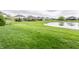 Expansive backyard featuring a serene pond, manicured lawn, and neighboring homes at 2785 W High Grove Cir, Zionsville, IN 46077