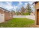 Large grassy backyard enclosed with a white vinyl fence, featuring a playhouse and brick house in the background at 3221 Washington St, Columbus, IN 47203