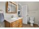 Well-lit bathroom featuring a wood vanity, medicine cabinet and a toilet near the door for convenience at 3221 Washington St, Columbus, IN 47203