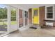 Charming enclosed front porch with a bright yellow door and cozy seating, perfect for welcoming guests at 3221 Washington St, Columbus, IN 47203