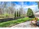 A well-manicured backyard has a paver patio, lush green grass, a wooden fence, and mature trees for privacy at 3466 Firethorn Dr, Whitestown, IN 46075